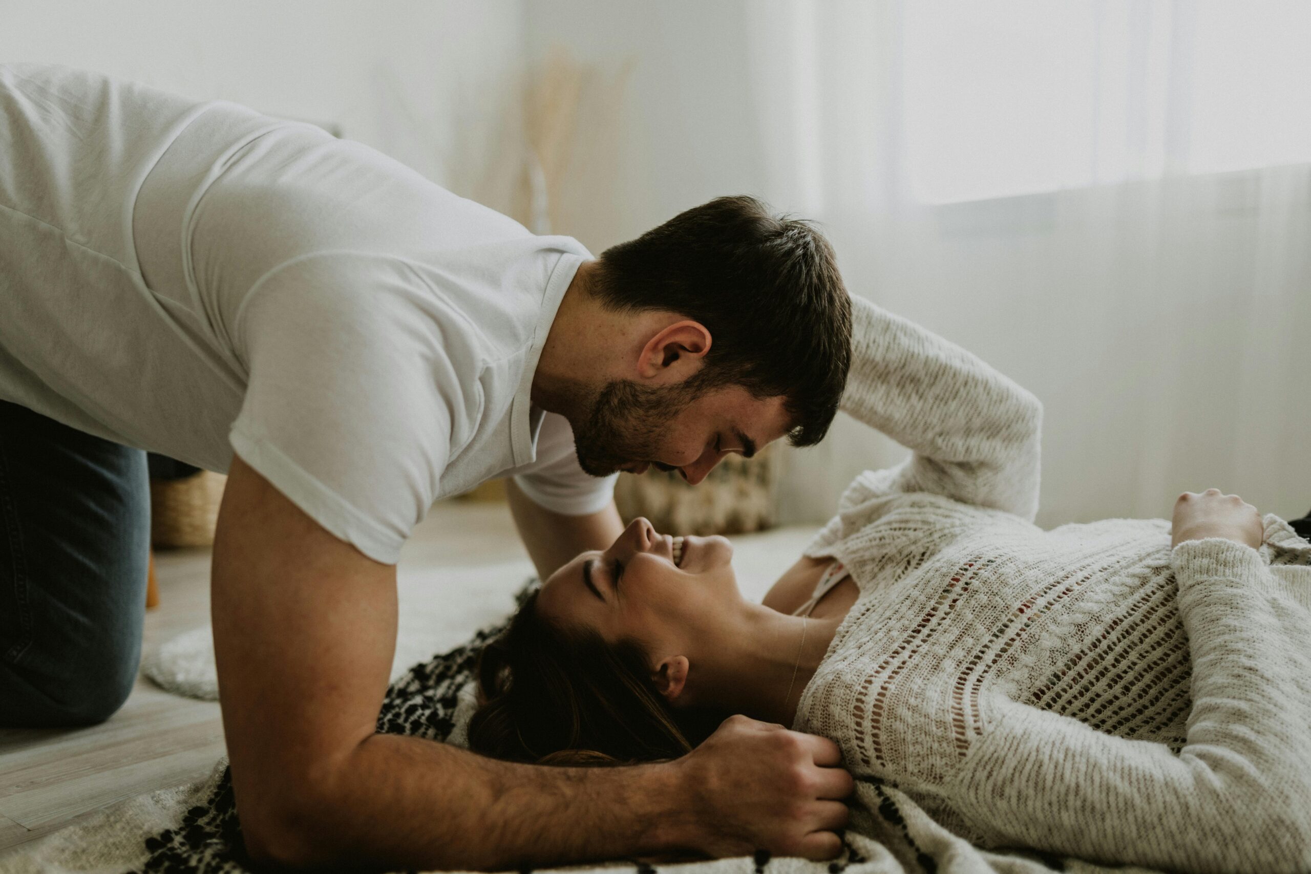 Young couple sharing a joyful and intimate moment together on the floor indoors.